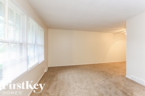 a spacious living room with a large window and carpeting
