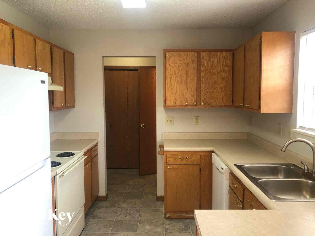 an empty kitchen with wooden cabinets and white appliances