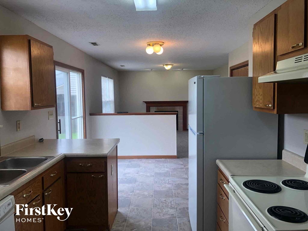 an empty kitchen with a white stove and refrigerator