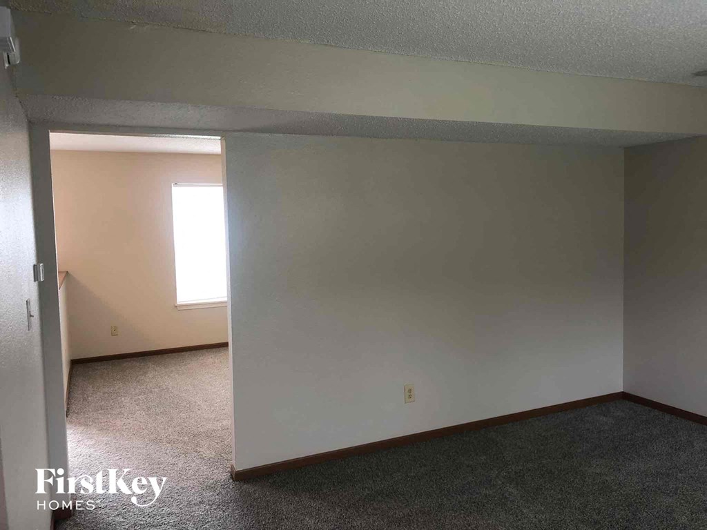 an empty living room with white walls and a window