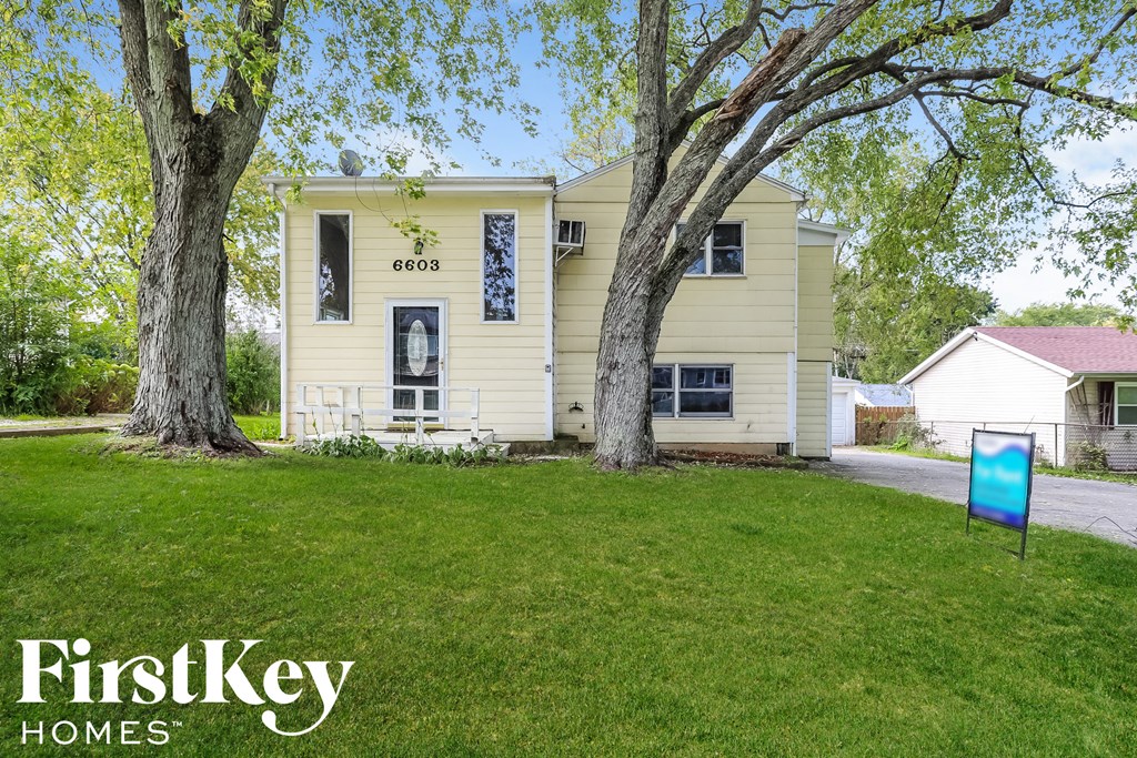 A yellow house with the number 6603 on it is for sale.