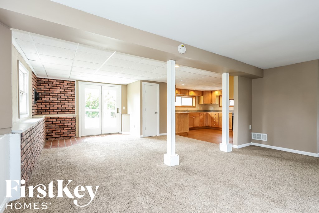 A spacious living room with a brick wall and a view of a kitchen.