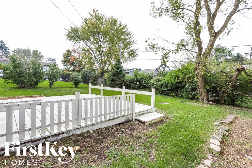 A white picket fence in a grassy area with trees in the background.