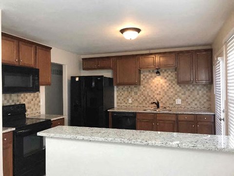 A kitchen with black appliances and brown cabinets.