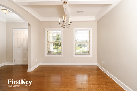 a empty dining room with a wood floor and two windows
