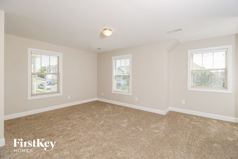 a spacious living room with carpet and two windows