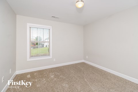 a spacious room with carpet and a window