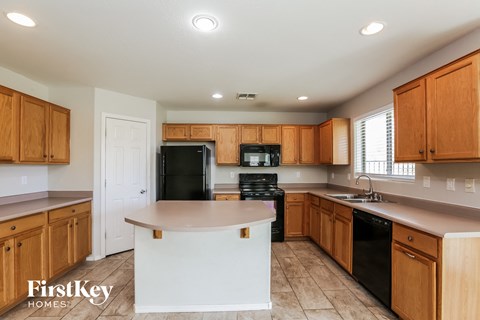 a kitchen with wooden cabinets and black appliances and a white island
