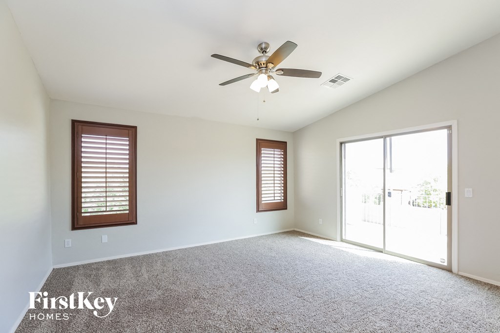 an empty living room with a ceiling fan and a window