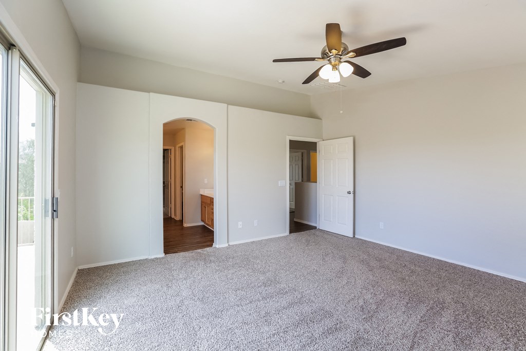 an empty living room with a ceiling fan and a carpeted floor