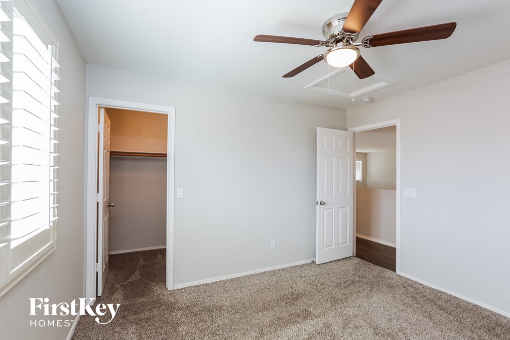 a bedroom with a ceiling fan and a closet