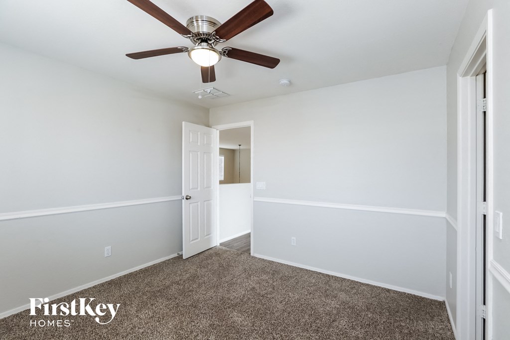 a bedroom with white walls and a ceiling fan