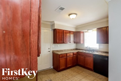 A kitchen with brown cabinets and a black dishwasher.