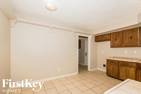 a kitchen with white walls and wooden cabinets and tiled floors