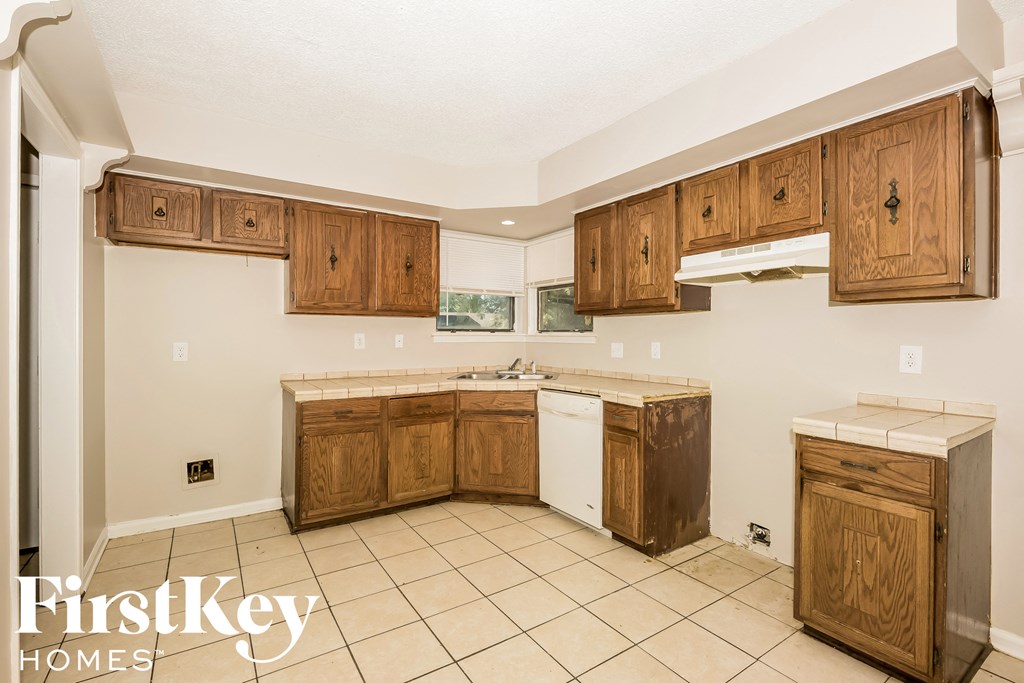 a kitchen with wooden cabinets and white appliances and tiled floors