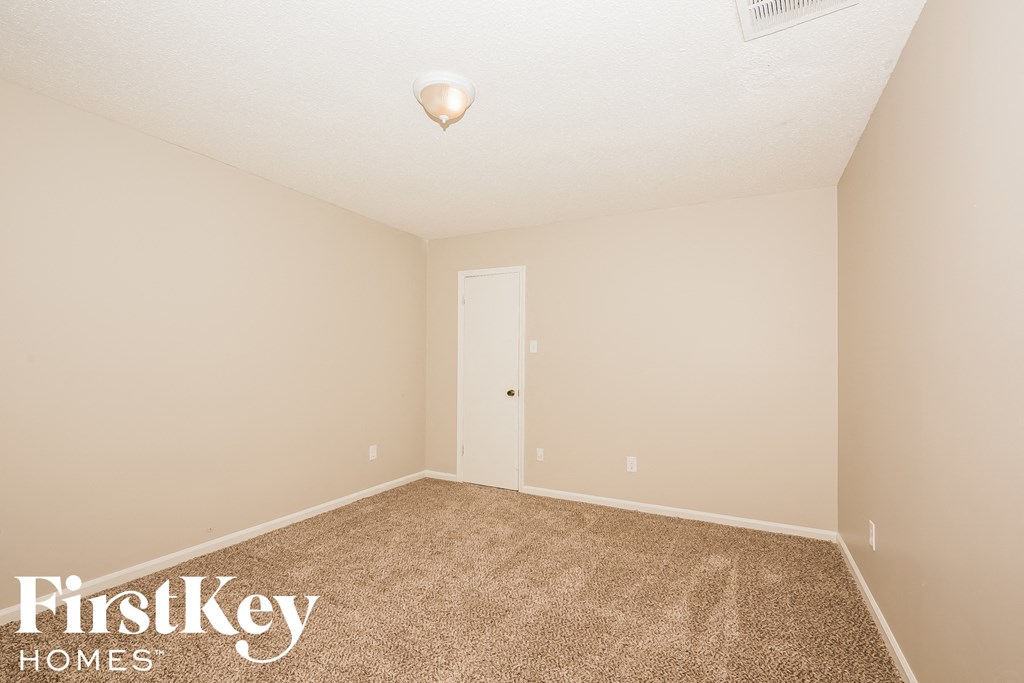 a bedroom with beige carpet and a white door