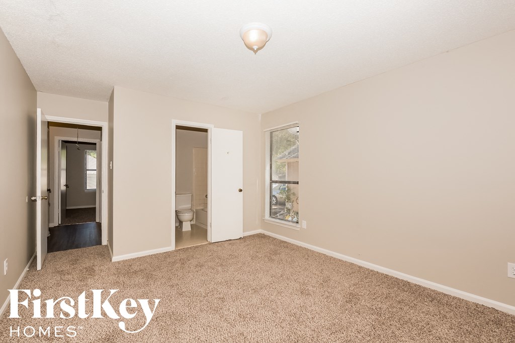 a bedroom with a carpeted floor and a door to a bathroom