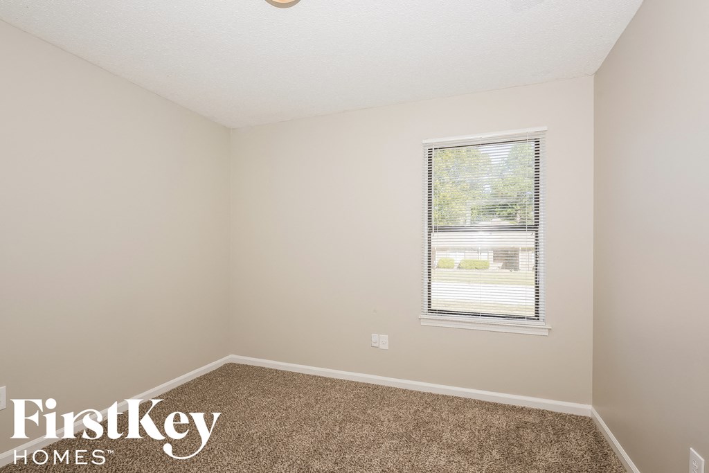 a small room with carpet and a window