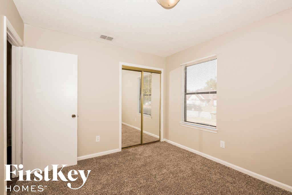 a bedroom with carpet and a door to a closet