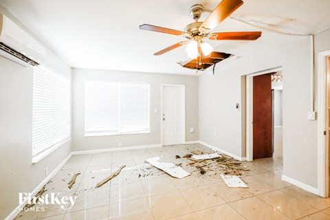a room with construction debris on the floor and a ceiling fan