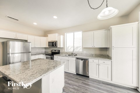 A modern kitchen with white cabinets and a marble countertop.