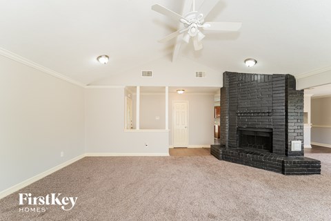 A living room with a fireplace and a ceiling fan.