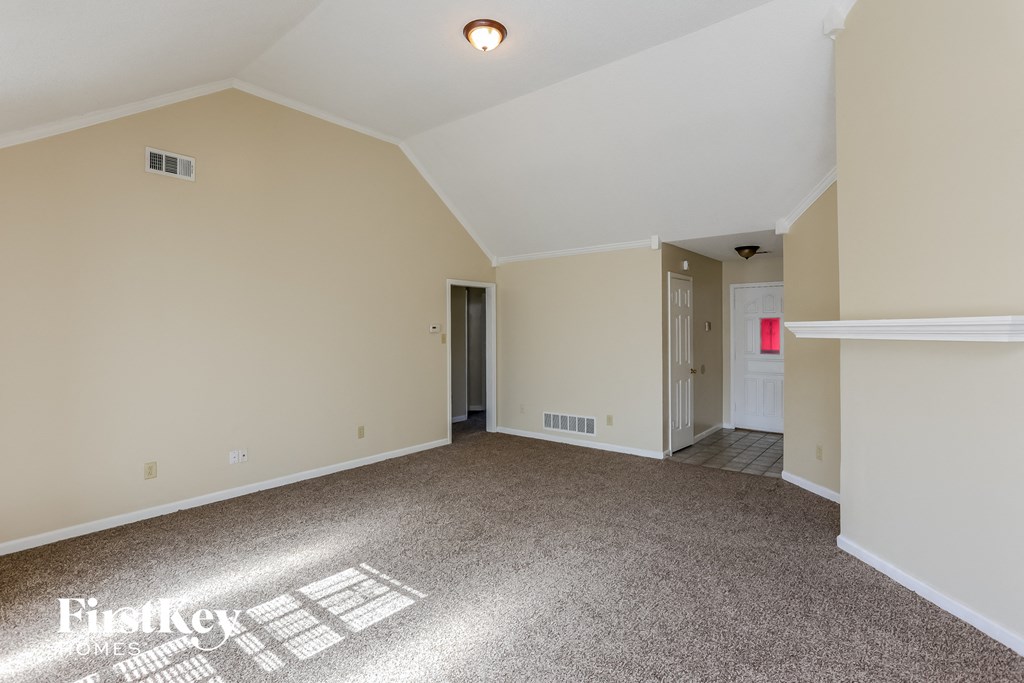 an empty living room with carpet and white walls