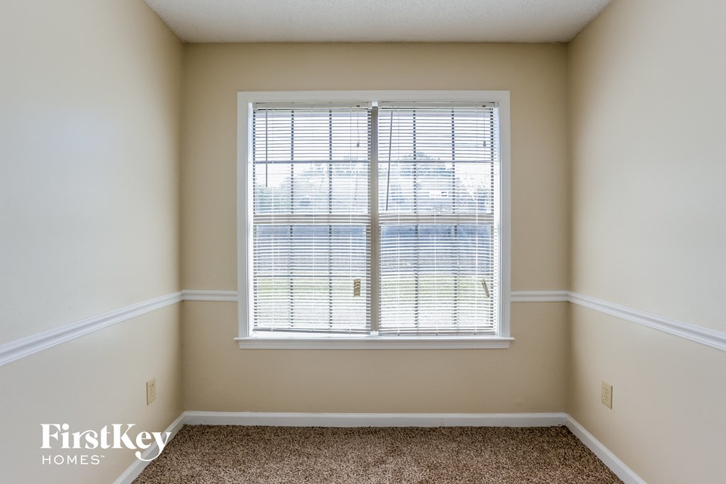 a bedroom with a large window and a carpeted floor