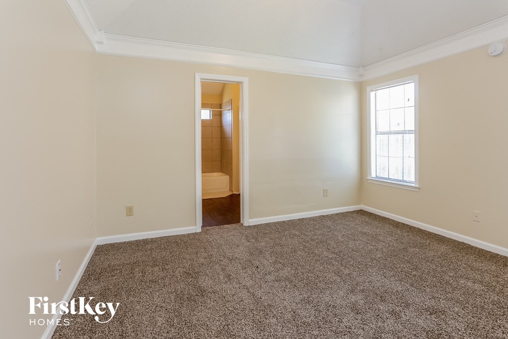 an empty living room with carpet and a door to a bathroom