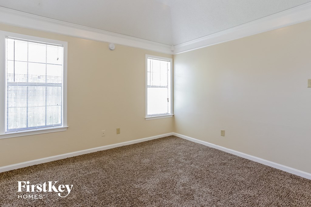 a empty room with carpet and two windows