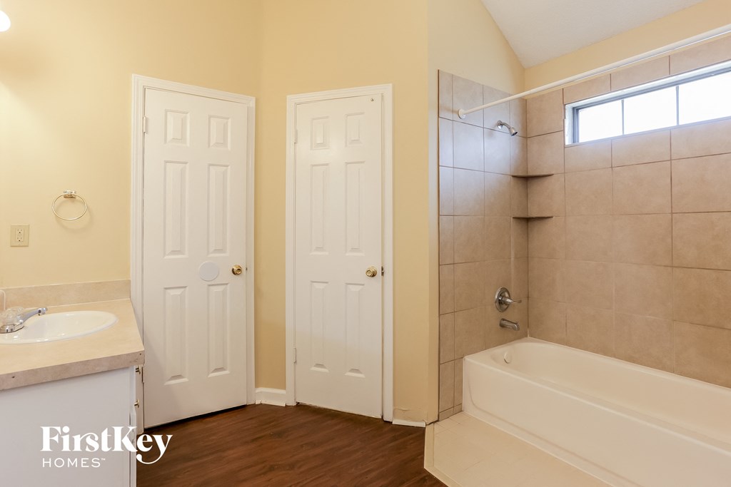 a bathroom with a tub and a sink and a shower and a door