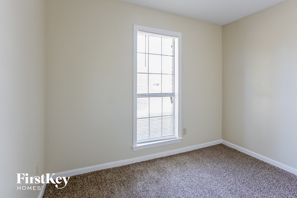 a bedroom with a window and a carpeted floor