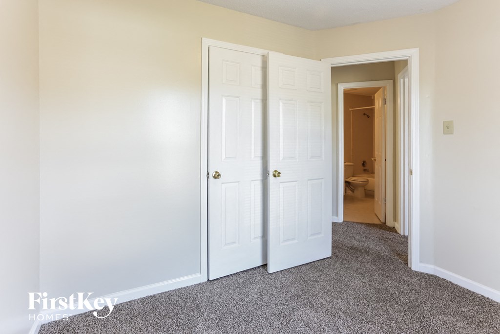 a closet with two doors and a hallway to a bathroom