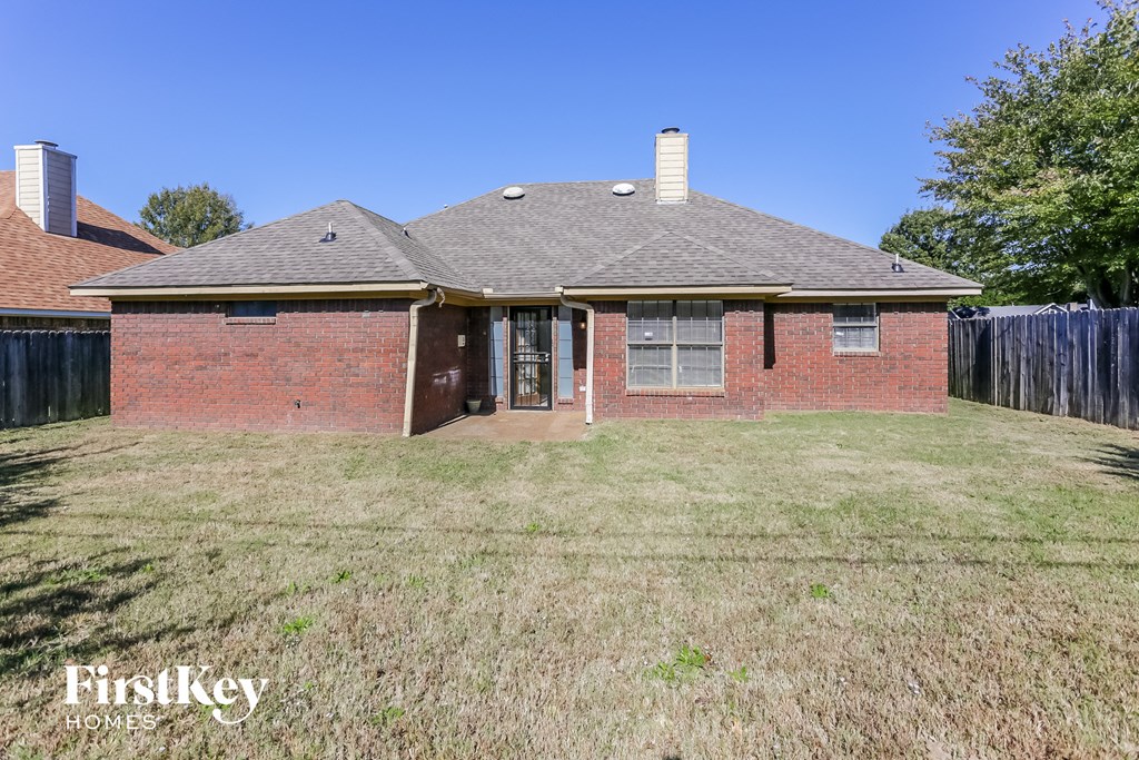 a small brick house with a yard and a fence