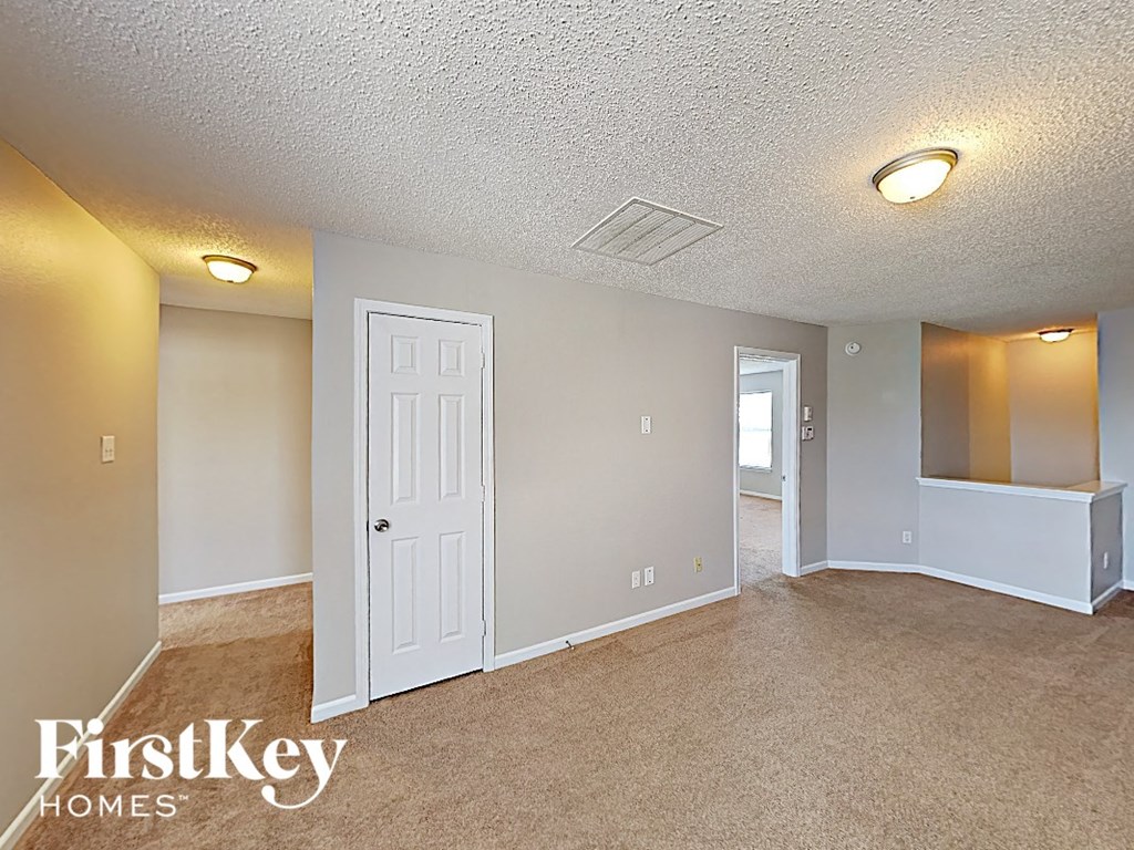 A room with a white door and a carpeted floor.