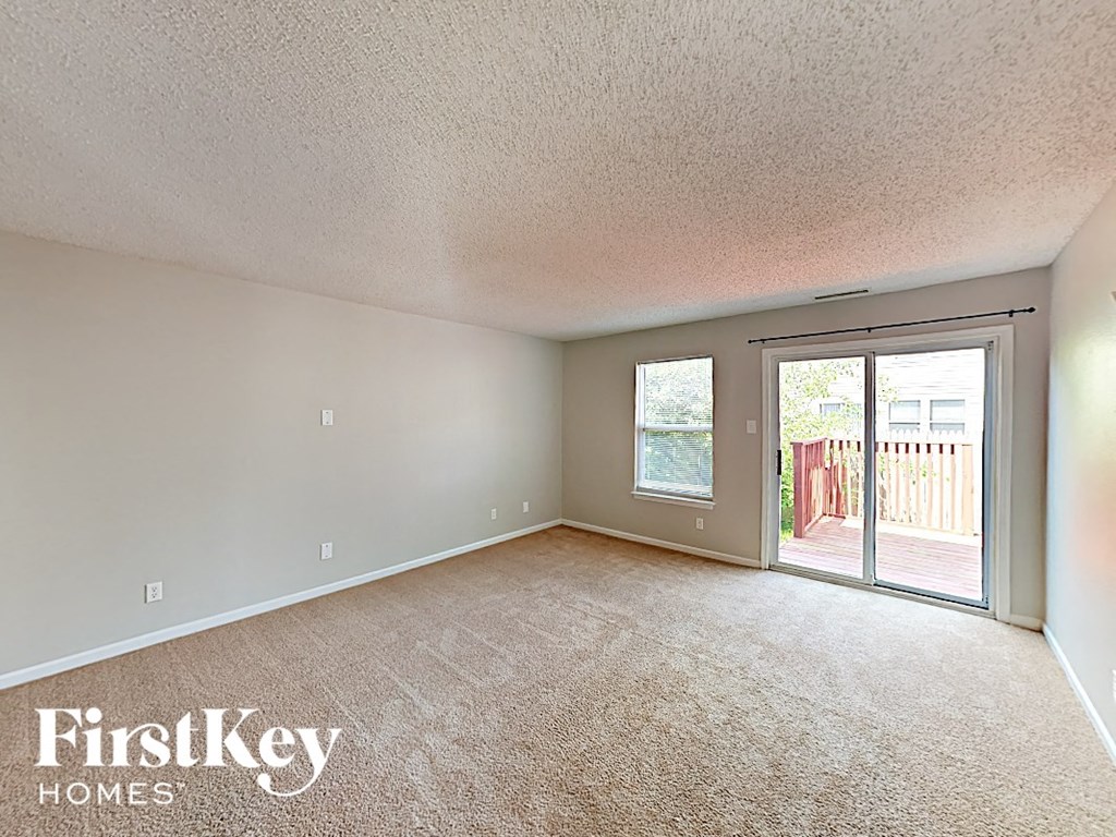 A room with a carpeted floor and a sliding glass door leading to a deck.