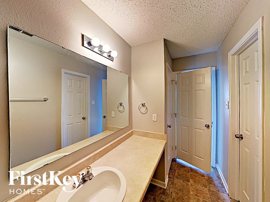 A bathroom with a sink, mirror, and lights.