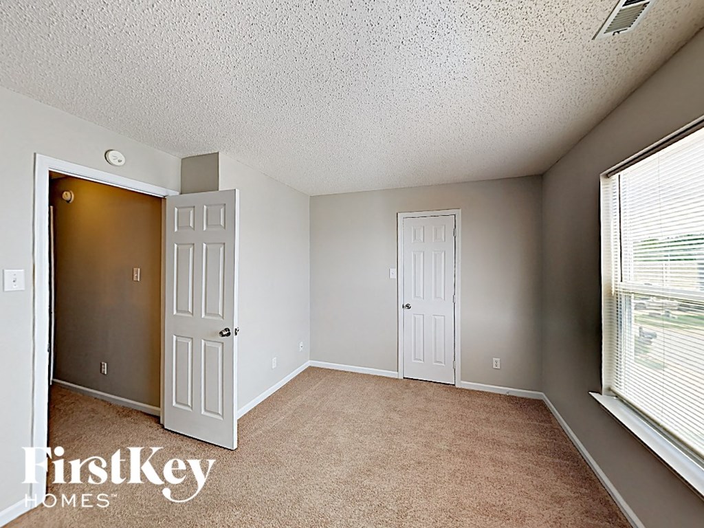 A room with a carpeted floor and two doors, one of which is open.