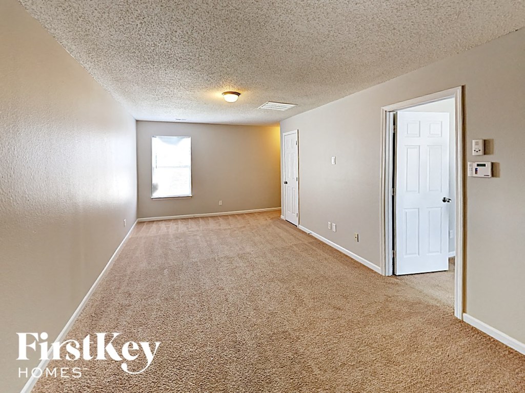 A carpeted room with a door and a window.