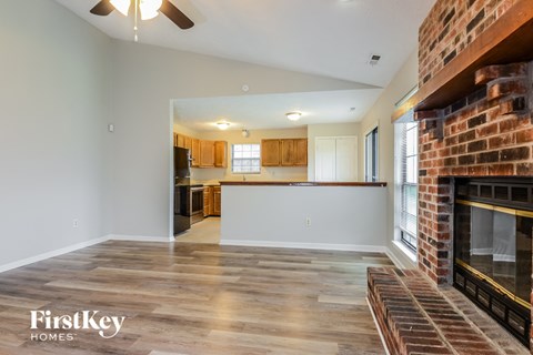A spacious living room with a brick fireplace and wooden flooring.