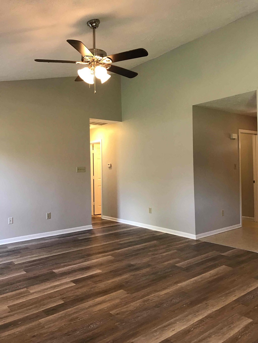 A room with a ceiling fan and wooden flooring.