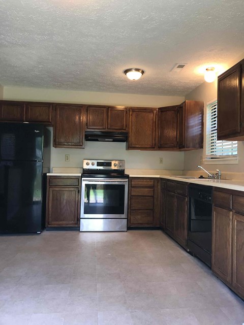 A kitchen with wooden cabinets and black appliances.