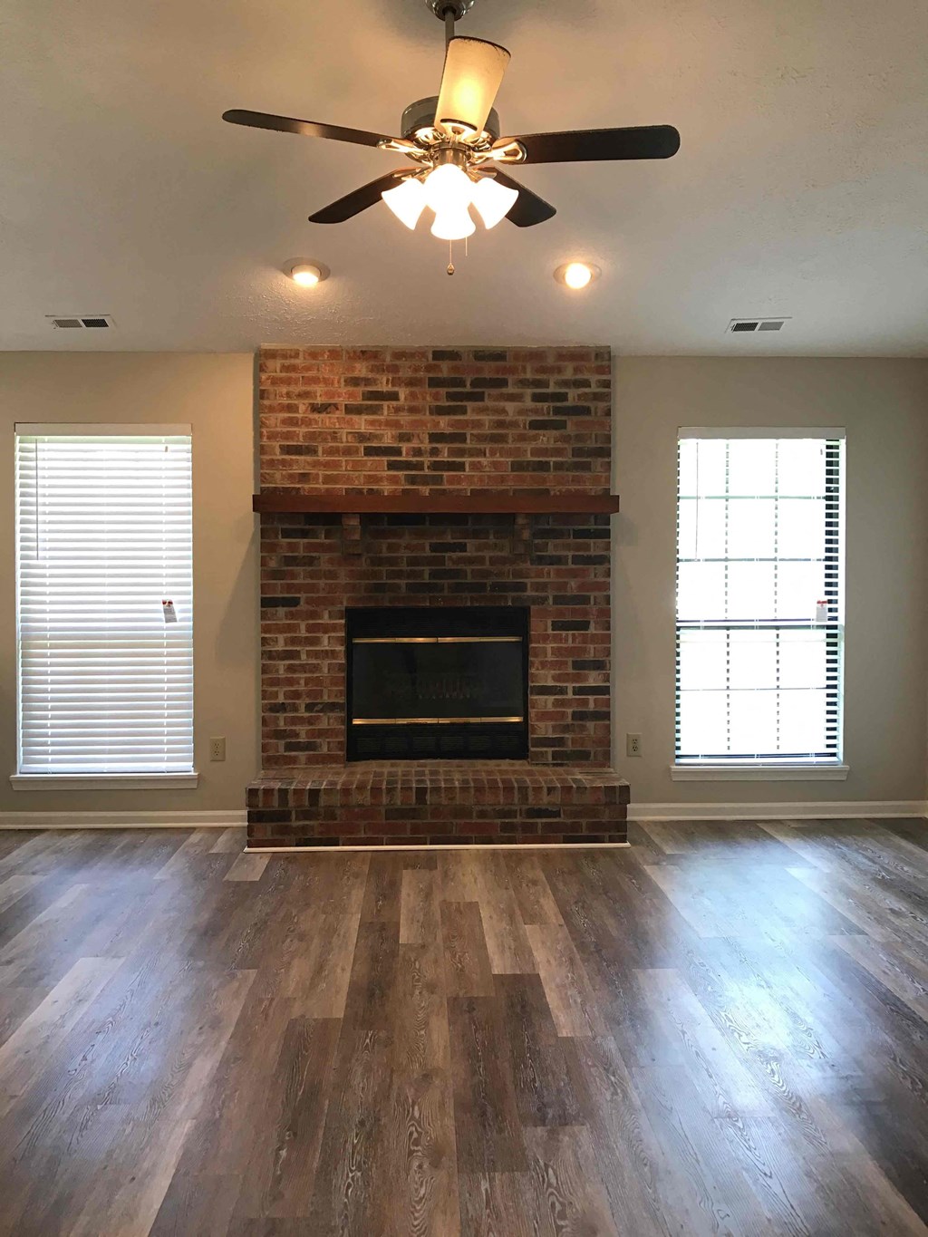 A room with a fireplace and a ceiling fan.
