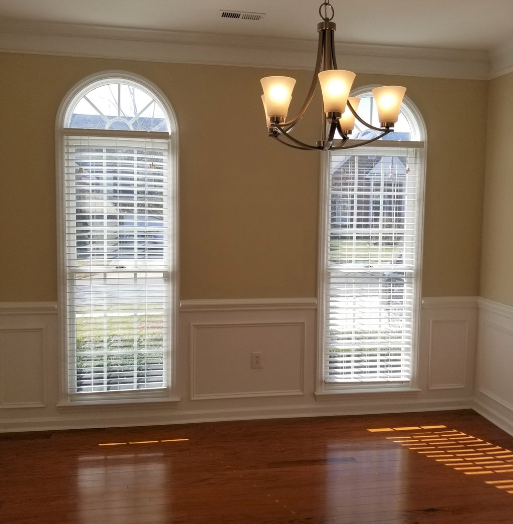 a dining room with two windows and a chandelier