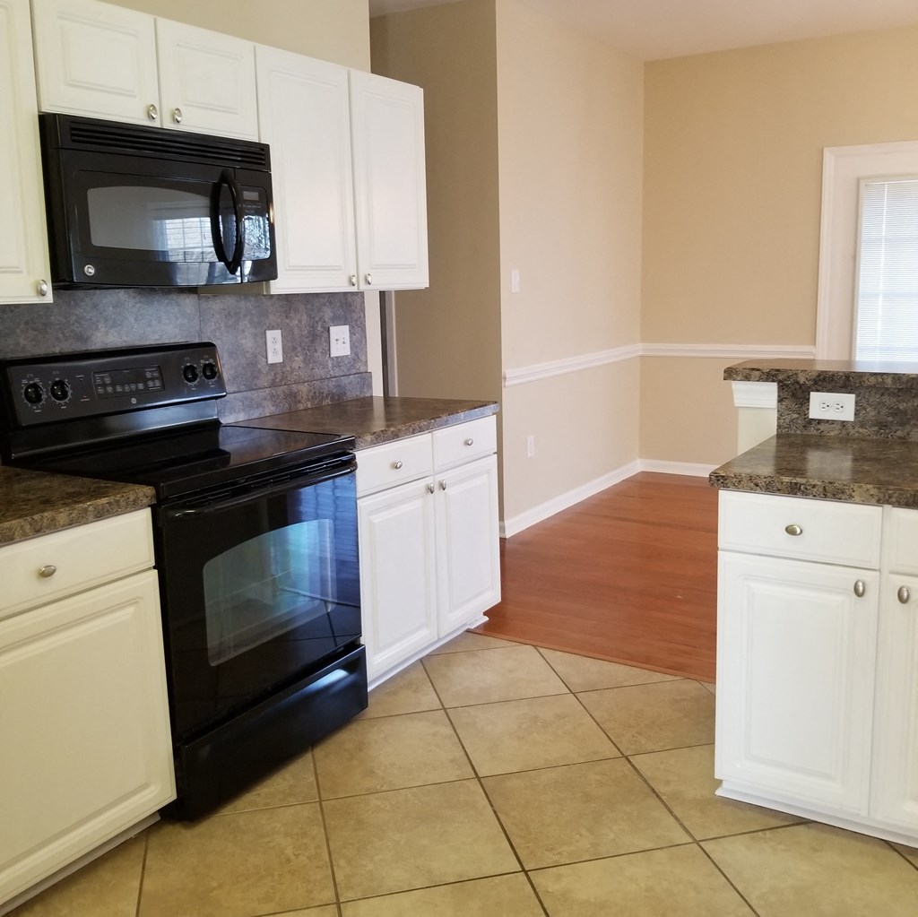 an empty kitchen with black appliances and white cabinets