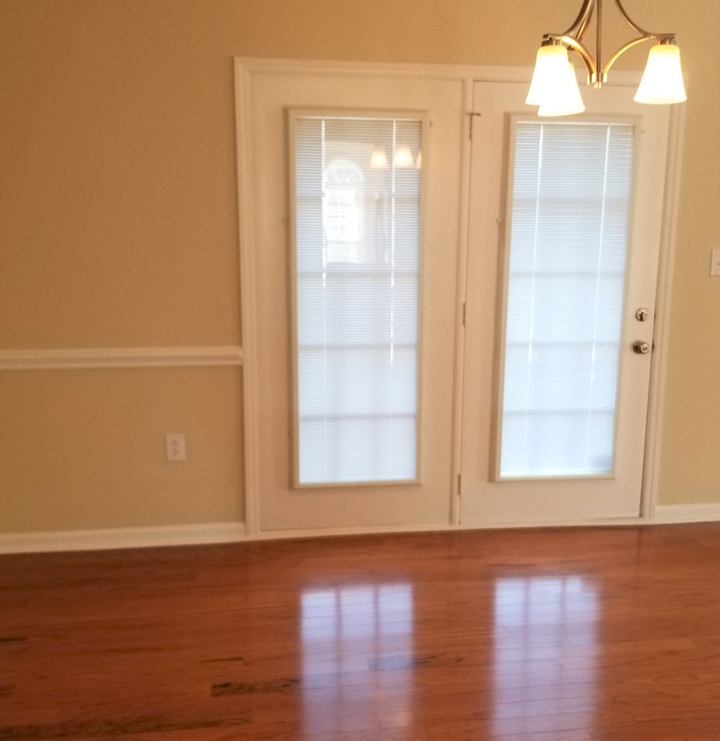 an empty living room with a hard wood floor and doors