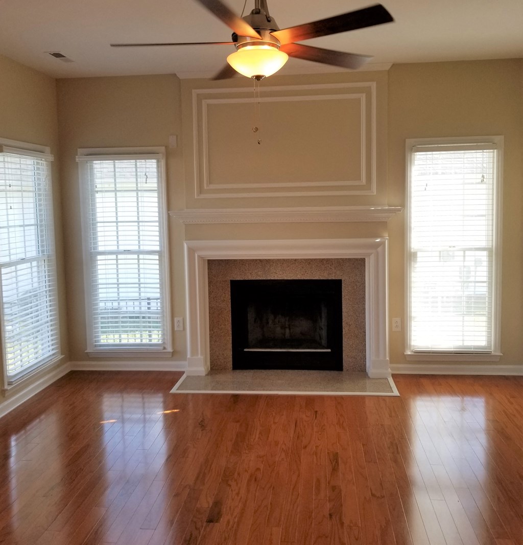 an empty living room with a fireplace and a ceiling fan