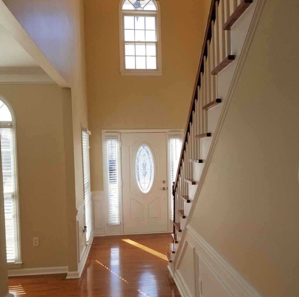 the view of the front door from the hallway of a house with a stairwell