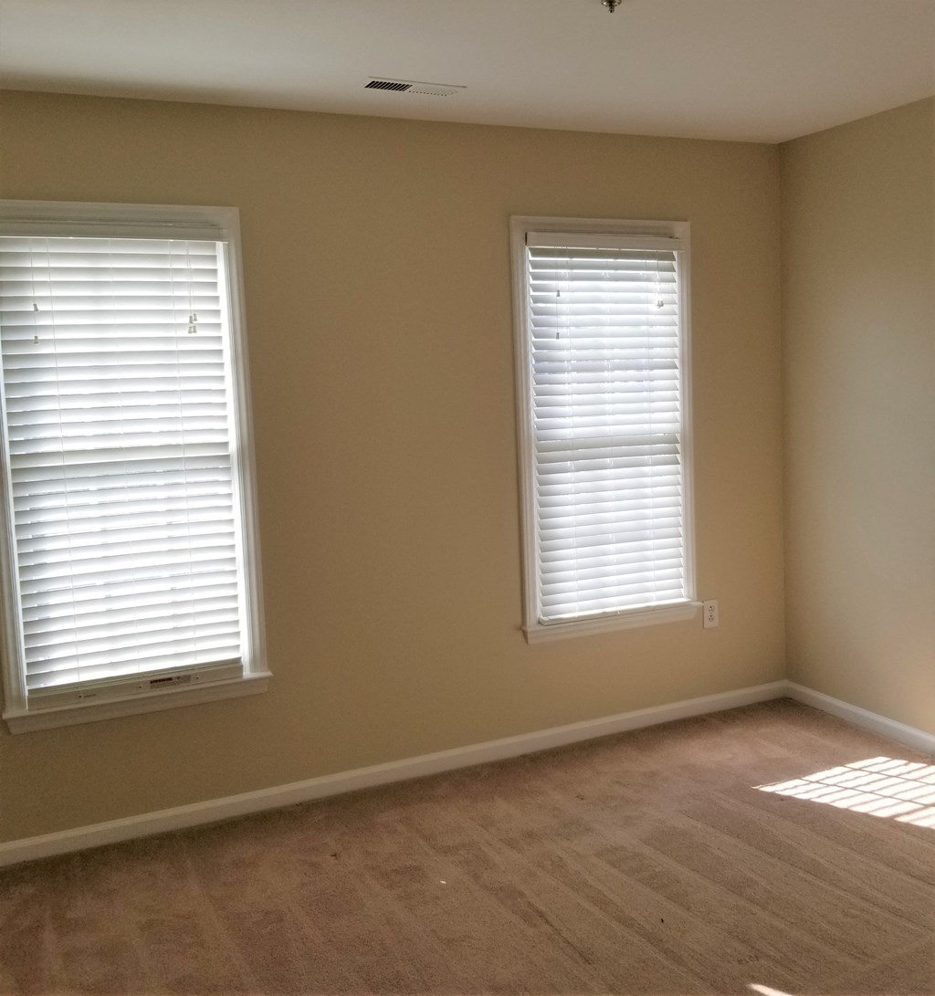 a living room with two windows and a wooden floor