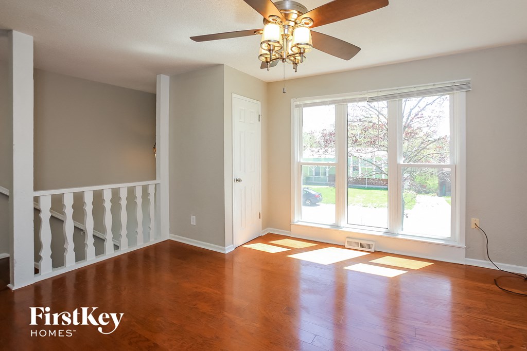 an empty living room with wood floors and a ceiling fan